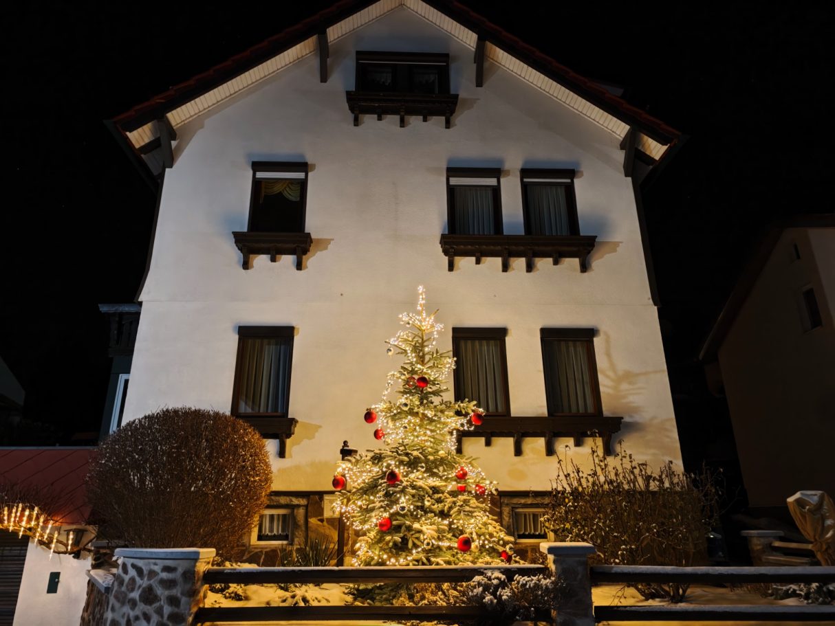 Bild vom Weihnachtsbaum vor dem Haus bei Abend mit Beleuchtung
